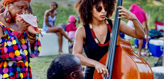 Sélène Saint-Aimé stands playing the upright bass, surrounded by other musicians
